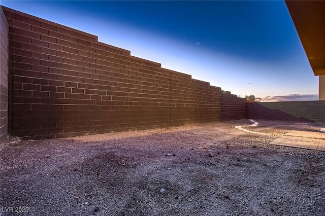 yard at dusk featuring a fenced backyard