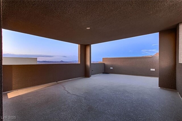 exterior space featuring a textured wall, a textured ceiling, and a healthy amount of sunlight