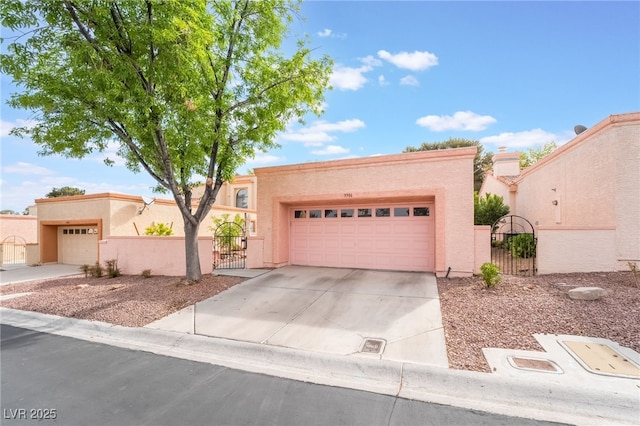 view of front of home featuring concrete driveway, a garage, stucco siding, and a gate