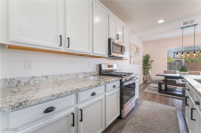 kitchen with white cabinets, dark wood-style flooring, appliances with stainless steel finishes, and visible vents