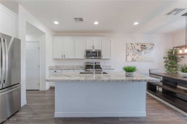 kitchen featuring visible vents, white cabinets, light stone counters, a sink, and stainless steel appliances