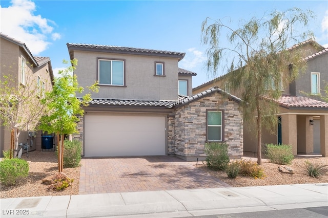 mediterranean / spanish home featuring a garage, stone siding, decorative driveway, stucco siding, and a tile roof
