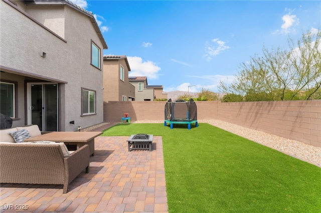 view of yard with a fire pit, a fenced backyard, a patio area, and a trampoline