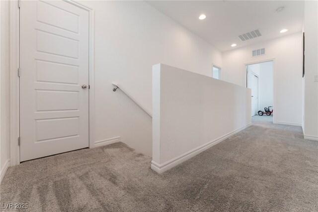 corridor with visible vents, carpet, and baseboards