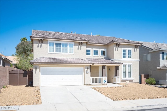 traditional-style house with concrete driveway, stucco siding, a gate, an attached garage, and fence