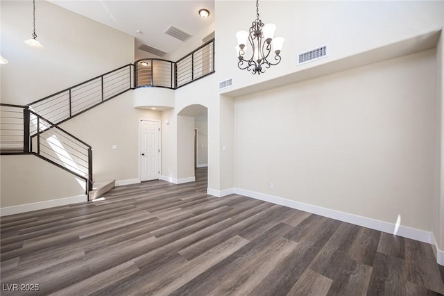 unfurnished living room featuring arched walkways, visible vents, stairs, and wood finished floors
