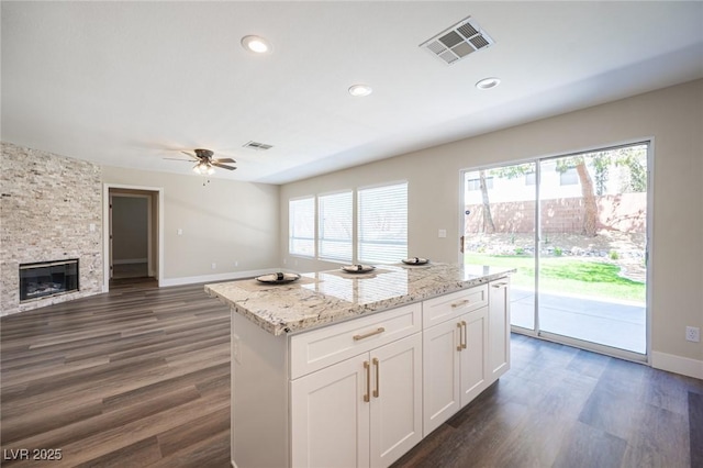 kitchen featuring baseboards, open floor plan, dark wood-style floors, visible vents, and ceiling fan