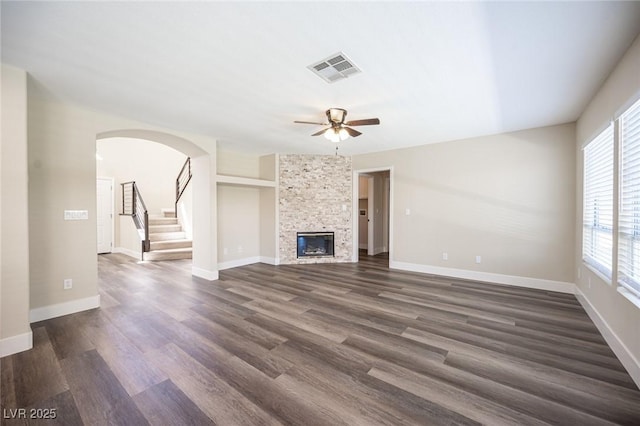 unfurnished living room featuring dark wood-style flooring, visible vents, a ceiling fan, and a fireplace