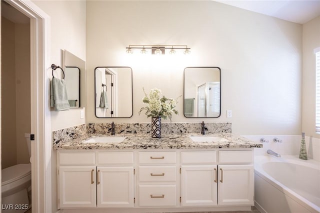bathroom featuring toilet, a garden tub, double vanity, and a sink