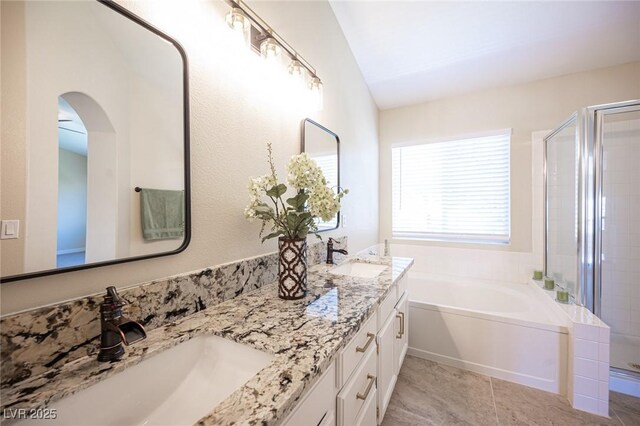 bathroom with double vanity, a garden tub, a sink, and a stall shower