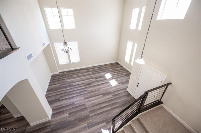 entryway featuring visible vents, a high ceiling, wood finished floors, baseboards, and a notable chandelier