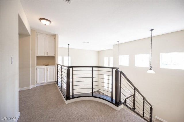 corridor featuring an upstairs landing, baseboards, and carpet