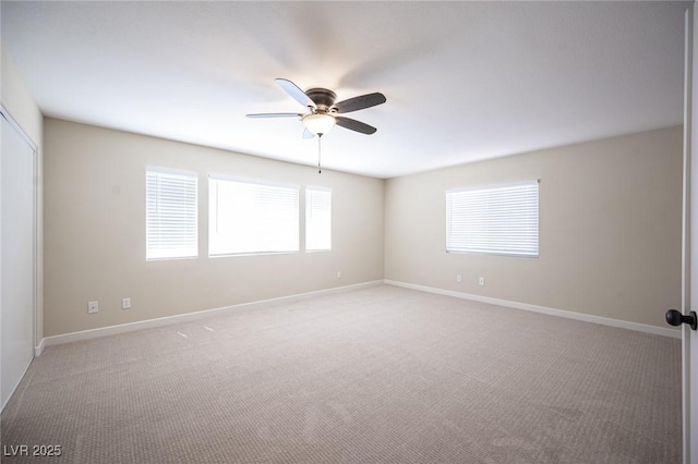 spare room featuring light carpet, baseboards, and a ceiling fan