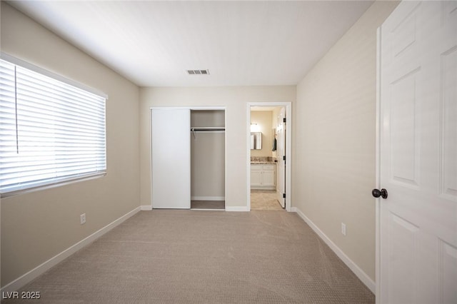 unfurnished bedroom featuring a closet, visible vents, light colored carpet, and baseboards