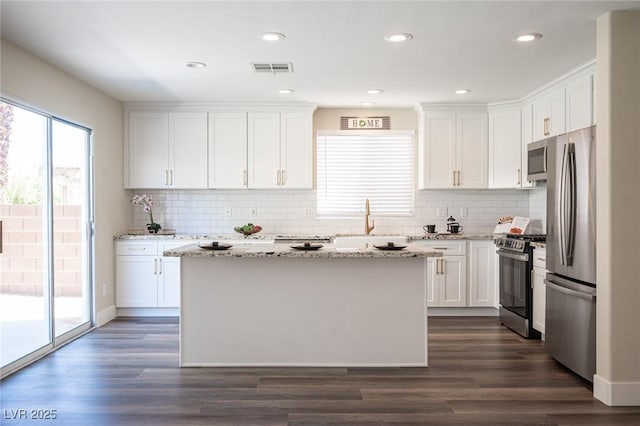 kitchen with white cabinetry, backsplash, and stainless steel appliances