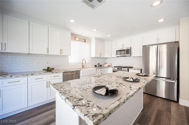kitchen featuring a sink, visible vents, dark wood-type flooring, and stainless steel appliances