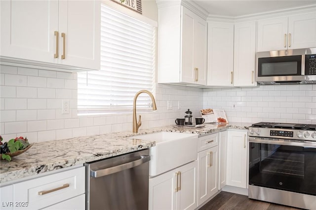 kitchen featuring backsplash, appliances with stainless steel finishes, a sink, and white cabinetry