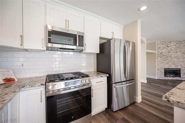 kitchen featuring dark wood-style flooring, white cabinetry, light stone counters, and stainless steel appliances