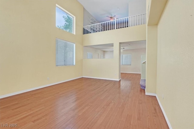 681 Peach Coral St, Las Vegas, NV 89183 - unfurnished living room featuring baseboards, a high ceiling, a ceiling fan, and light wood-style flooring