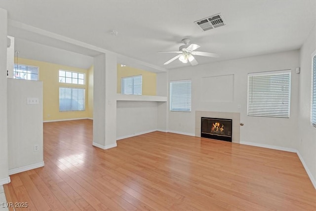 681 Peach Coral St, Las Vegas, NV 89183 - unfurnished living room featuring ceiling fan, visible vents, a tiled fireplace, baseboards, and light wood-style floors