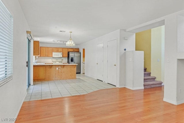 681 Peach Coral St, Las Vegas, NV 89183 - kitchen with stainless steel fridge, light countertops, range, a peninsula, and white microwave