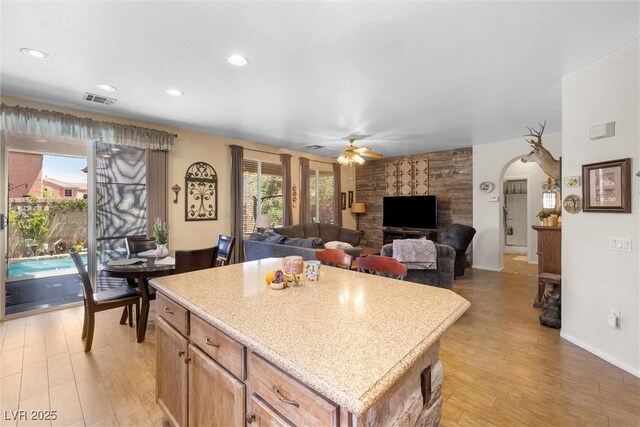 648 Sunrise Lake Pl, Henderson, NV 89002 - kitchen with light countertops, arched walkways, a ceiling fan, a kitchen island, and visible vents