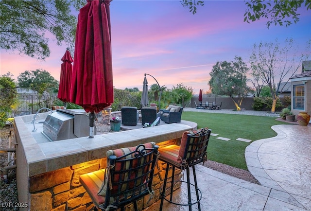 9 Contra Costa Pl, Henderson, NV 89052 - patio terrace at dusk featuring grilling area, a yard, outdoor wet bar, and a fenced backyard