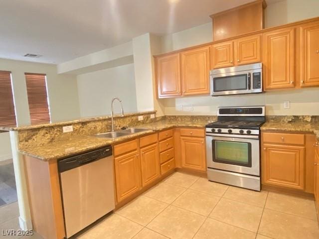 8374 Pioneer Way, Las Vegas, NV 89113 - kitchen with a peninsula, light tile patterned floors, light stone countertops, appliances with stainless steel finishes, and a sink