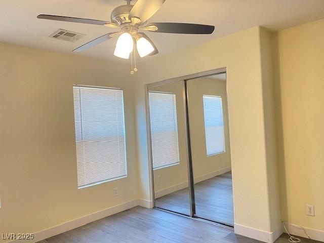 8374 Pioneer Way, Las Vegas, NV 89113 - unfurnished bedroom with visible vents, baseboards, a closet, ceiling fan, and wood finished floors