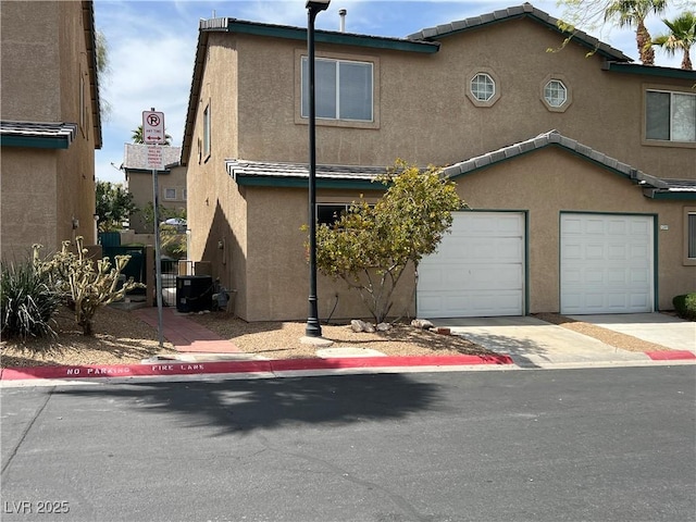 multi unit property featuring a garage, driveway, and stucco siding