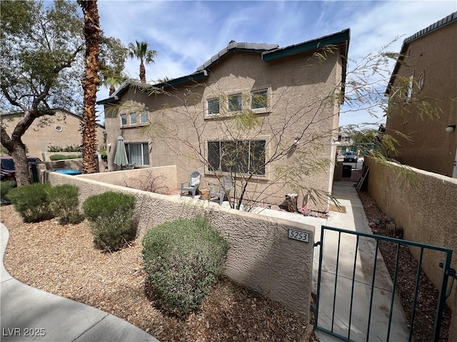 view of front of home with stucco siding, fence, and a gate
