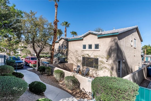 view of side of home featuring a tiled roof, fence, and stucco siding