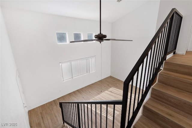 stairway with wood finished floors and a ceiling fan