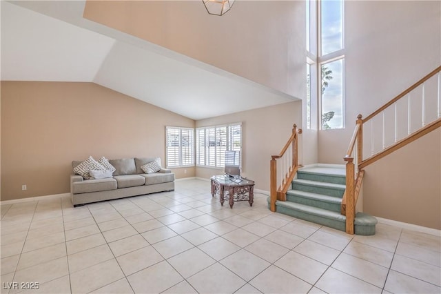 living room featuring high vaulted ceiling, stairs, light tile patterned floors, and baseboards