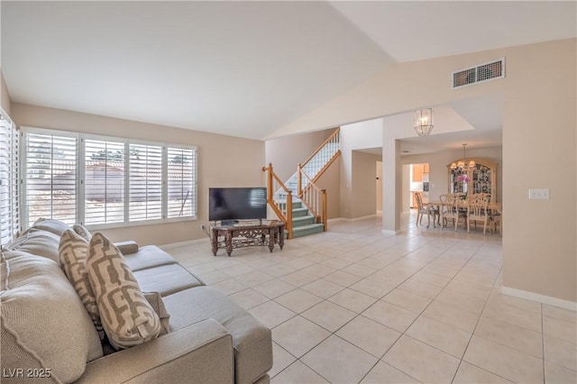 living area with a chandelier, light tile patterned floors, stairway, visible vents, and lofted ceiling