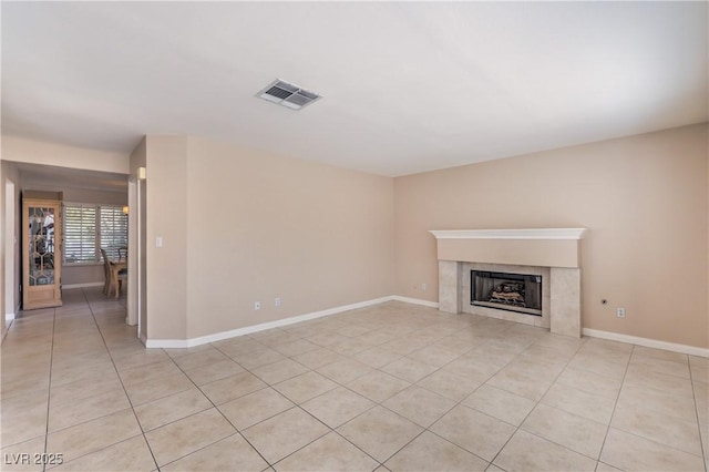 unfurnished living room featuring baseboards, light tile patterned floors, a tiled fireplace, and visible vents