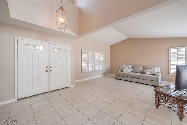 foyer featuring an inviting chandelier, light tile patterned floors, baseboards, and vaulted ceiling
