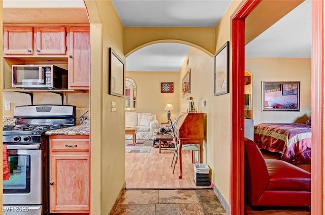 9000 Las Vegas Blvd Unit 1047, Las Vegas, NV 89123 - kitchen with stone finish floor, stainless steel appliances, baseboards, arched walkways, and light stone countertops
