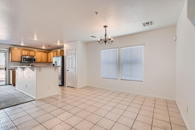 kitchen featuring visible vents, an inviting chandelier, light countertops, appliances with stainless steel finishes, and a breakfast bar area