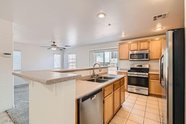 kitchen with visible vents, appliances with stainless steel finishes, light tile patterned flooring, light countertops, and a sink