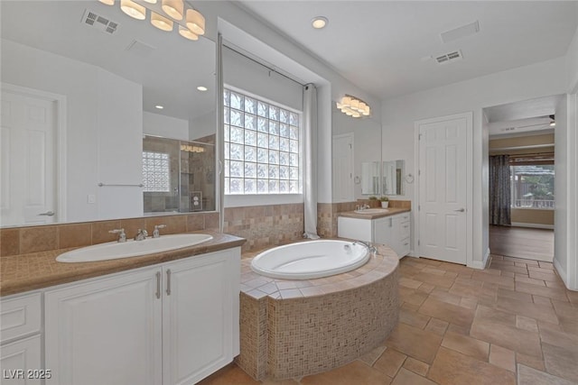 8209 Chapelle Ct, Las Vegas, NV 89131 - bathroom featuring a shower stall, two vanities, a garden tub, and stone finish floors