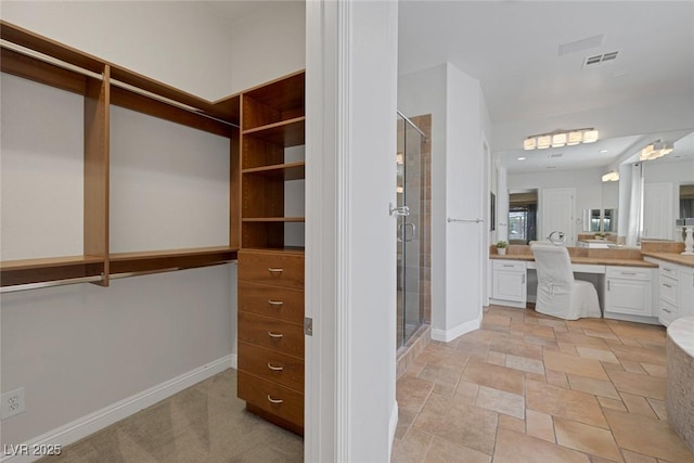 8209 Chapelle Ct, Las Vegas, NV 89131 - walk in closet featuring built in desk and light stone finish flooring