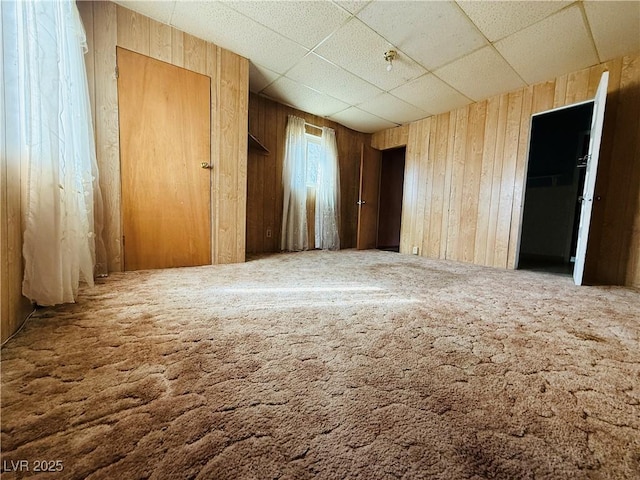 spare room featuring wood walls and a drop ceiling