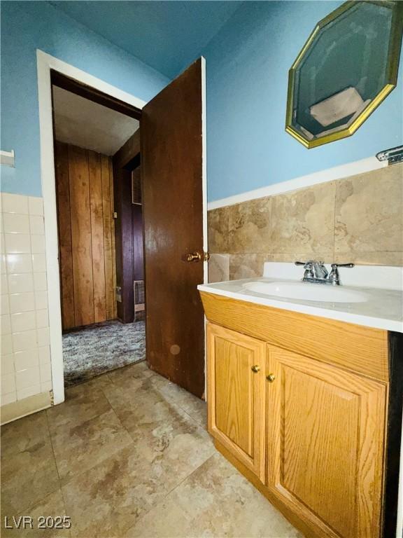 bathroom with vanity, a wainscoted wall, and tile walls