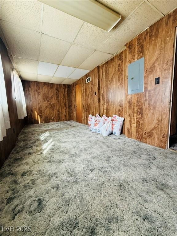 interior space with wood walls, a paneled ceiling, and electric panel