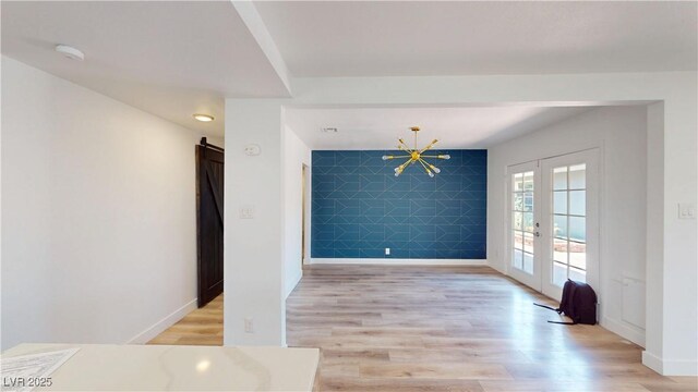 1801 Griffith Ave, Las Vegas, NV 89104 - empty room featuring french doors, an accent wall, light wood-style floors, a chandelier, and a smoke detector
