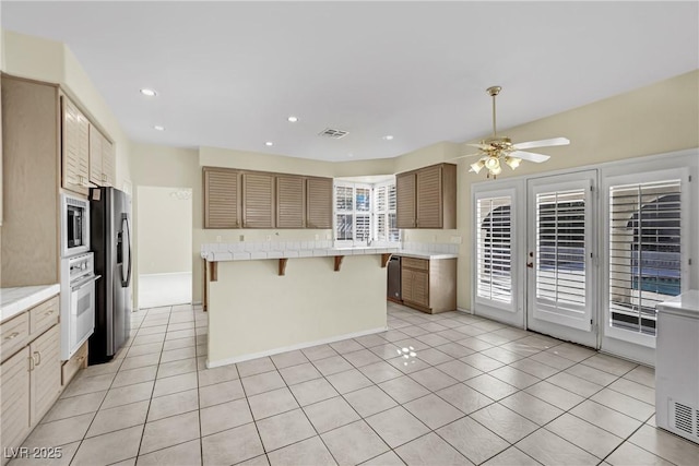 3755 Broadmead St, Las Vegas, NV 89147 - kitchen featuring stainless steel appliances, a kitchen bar, light tile patterned floors, ceiling fan, and a kitchen island