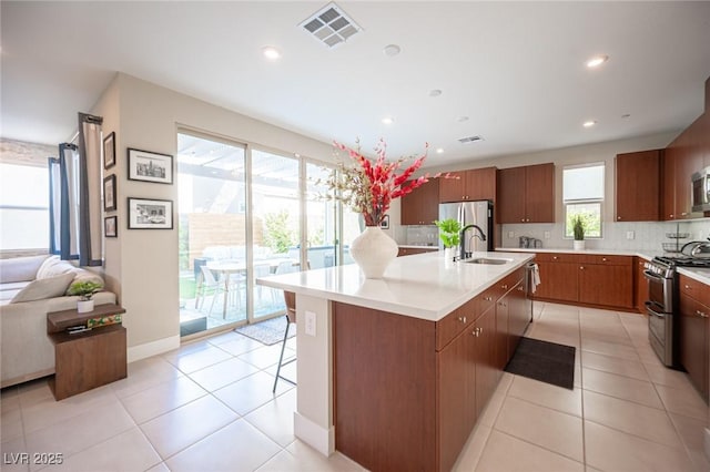 kitchen with appliances with stainless steel finishes, light tile patterned floors, a sink, and visible vents