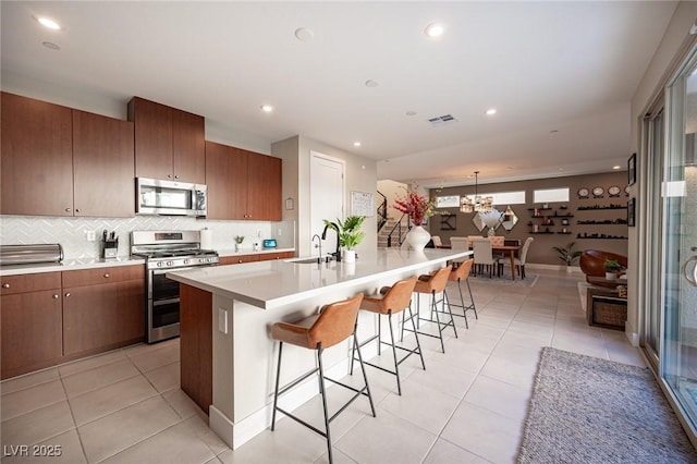 kitchen with light tile patterned flooring, light countertops, a breakfast bar area, and appliances with stainless steel finishes
