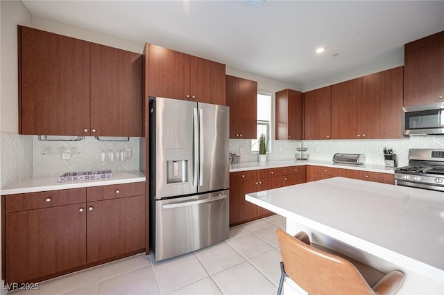 kitchen featuring backsplash, light countertops, light tile patterned flooring, and stainless steel appliances